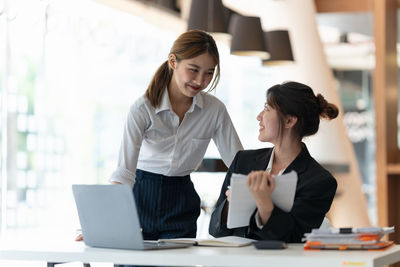 Businesswoman using laptop while standing in office