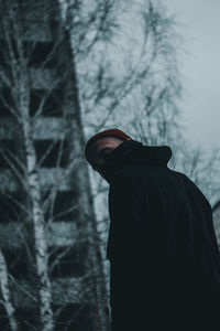 Midsection of person standing against trees during winter