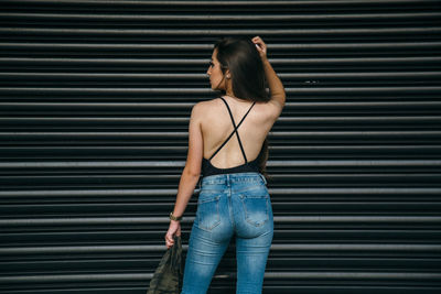 Rear view of woman standing against wall