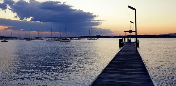 Pier over sea against sky during sunset