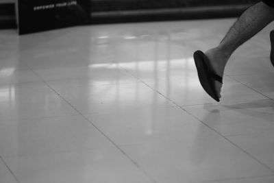 Low section of person walking on tiled floor