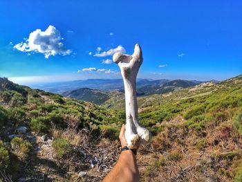 Midsection of woman against mountain range against blue sky