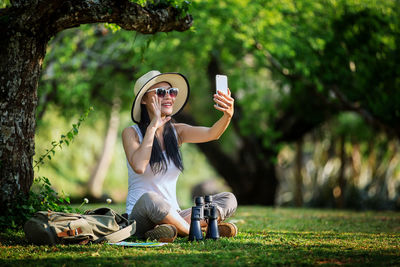 Full length of young woman taking selfie from mobile phone on field