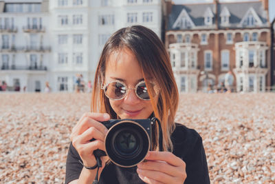 Asian woman taking photos with her camera on the beach