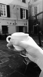 Cropped hand holding coffee at sidewalk cafe