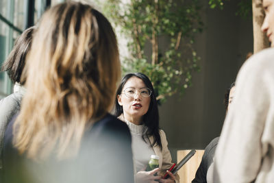 Female professional discussing with coworkers in meeting at conference event