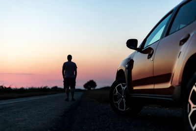 Rear view of silhouette man standing on road against sky