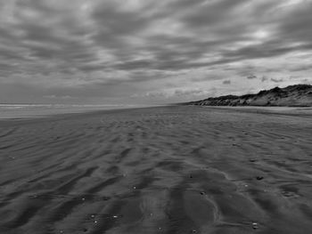 Idyllic view of sandy beach against cloudy sky