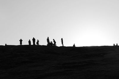 Silhouette people on landscape against clear sky