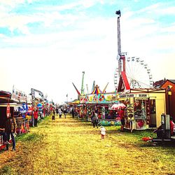 People at amusement park against sky