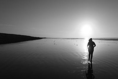 Rear view of silhouette man walking on beach