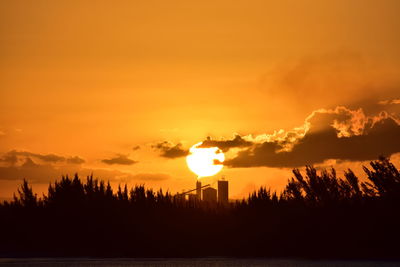 Silhouette trees on landscape against romantic sky at sunset