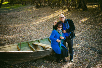 Portrait of smiling mature couple by boat at forest during autumn