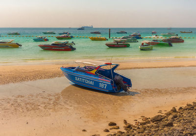 Boats moored on shore against sky