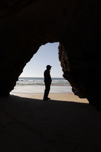 Silhouette man standing on rock at beach