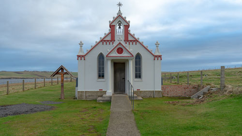 Traditional building on field against sky