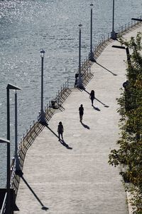 High angle view of people walking on footpath by sea