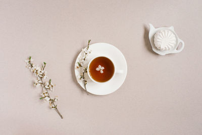 The concept of spring. a cup of black tea with apple blossoms and marshmallows on a teapot plate 