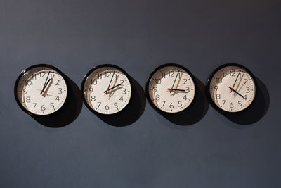 Four clocks on the black wall showing time with difference in an hour