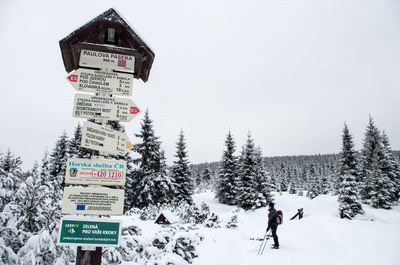 People crossing sign against clear sky during winter