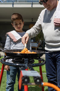 Grandfather and grandson preparing a paella in the garden