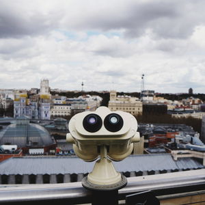 Close-up of coin-operated binoculars against buildings in city