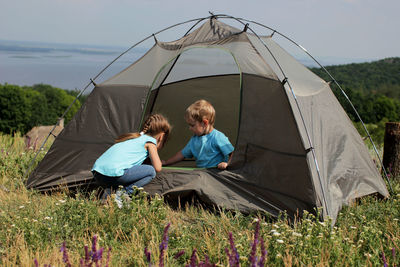 Cute sibling sitting in tent during camping