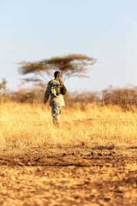 Full length of man standing on field against clear sky