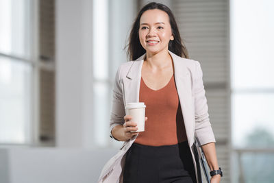 Portrait of a smiling young woman with coffee cup