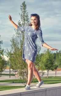 Beautiful woman wearing dress with eiffel tower pattern balancing on retaining wall