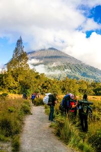 Rear view of people walking on mountain against sky