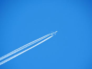 Low angle view of airplane flying against clear blue sky