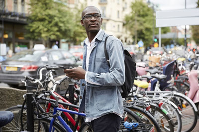 Mid adult businessman looking away while standing by bicycles in city