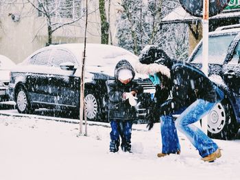 Mother with son on snow covered sidewalk during snow fall