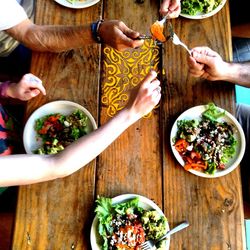 Cropped hands of friends toasting food over table