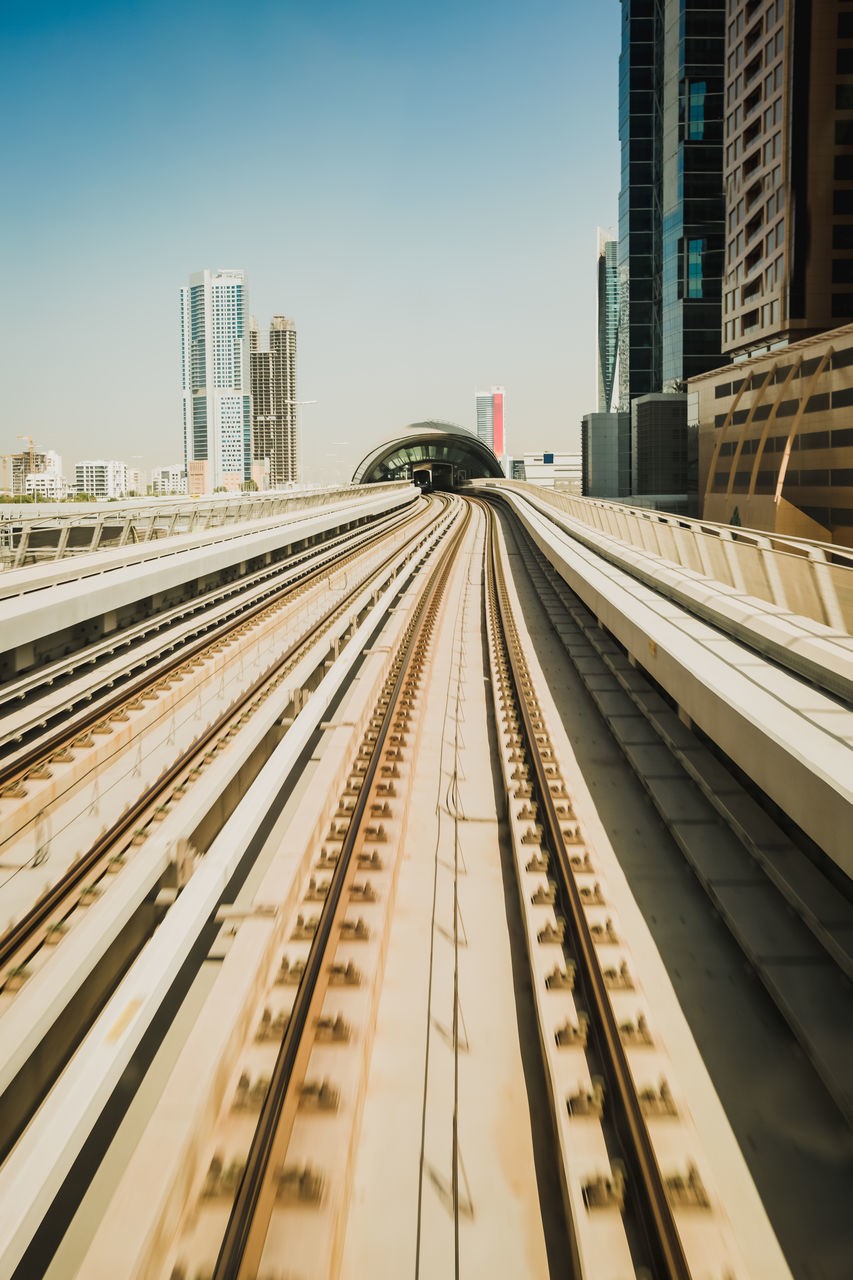 Railroad tracks in city against clear sky