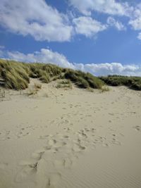 Footprints on sand at beach against sky