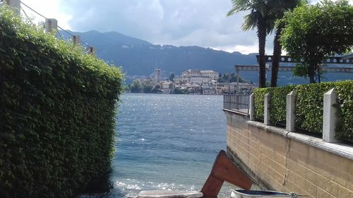 View of city at waterfront against cloudy sky