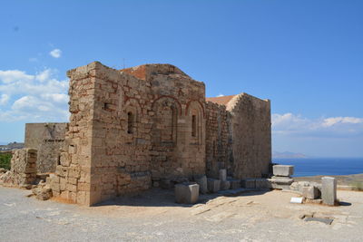 Old ruin building by sea against blue sky