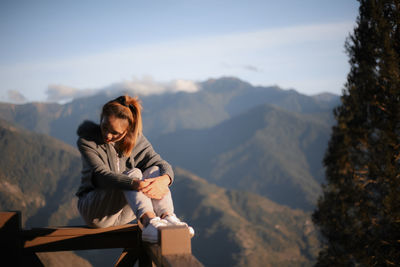 Man sitting on rock against mountains