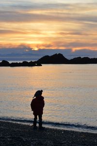 Silhouette man on beach against sky during sunset