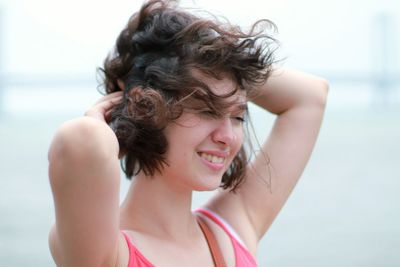 Close-up of smiling young woman with hands in hair