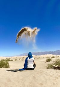 Rear view of man sitting on desert