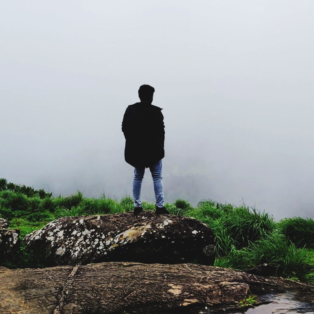 one person, standing, full length, rear view, real people, fog, lifestyles, nature, solid, leisure activity, plant, beauty in nature, rock - object, rock, men, day, tranquility, casual clothing, land, outdoors, looking at view