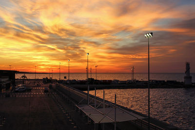 Street by sea against orange sky