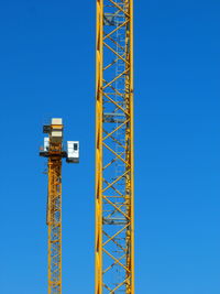 Low angle view of crane against clear blue sky