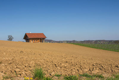 House on field against clear blue sky