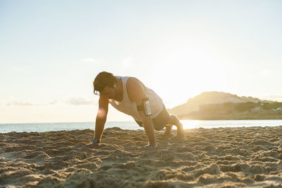 Spain, mallorca, jogger at the beach at sunrise, pushups