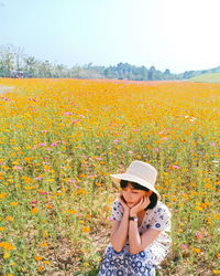 Young woman with yellow flowers on field