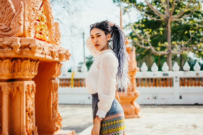 Young woman standing against wall